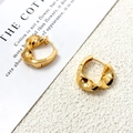 Detalle macro de pendientes de aro retorcidos bañados en oro de 18 quilates - Dorado