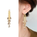Largos pendientes dorados de borla con cristales mostrados en modelo y fondo blanco - Estilo de Borla de Gota de Agua de Varias Capas (A1401-06B) / Dorado