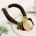 Close-up of bohemian woven rope necklace with lotus-shaped pendant and golden charms - Multicolor