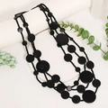 Collana a strati con perline nere opache e dischi di legno su oggetti di scena bianchi - Stile Nero (X-1198)