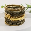 Dettaglio di bracciali bohémien a strati dorati con perline e trame a fune intrecciata - Stile Girasole Oro Vintage (S-515)