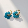 Close-up of bright blue hollow flower charms on gold stainless steel hoop earrings - Gold-Blue