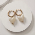 Detalle de pendientes de corazón dorados con colgantes de resina jaspeada sobre piedra - Blanco Roto