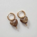 Gros plan détaillé de boucles d'oreilles dorées avec pendentifs cœurs en résine marbrée - Café