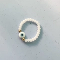 Handmade elastic beaded ring featuring white faceted beads and a light blue Evil Eye charm - White
