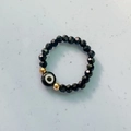 Ethnic elastic beaded ring featuring black faceted beads and a blue evil eye focal point - Black