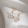 Detail of gold flower earrings with cat eye stones on elegant white silk background - Transparent Four-Leaf Heart