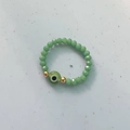 Light green beaded elastic ring with evil eye charm and golden metal accents - Green