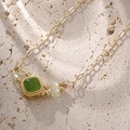 Vintage gold necklace with square green gemstone pendant on natural stone surface - Green Gold