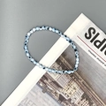 Macro detail of elastic beaded bracelet with light blue translucent evil eye glass beads - Blue & White