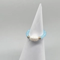Detail of a light blue beaded stretch ring with a freshwater pearl on a white cone stand - Lake Blue