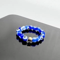 Close-up of blue glass evil eye beaded elastic ring with a central gold metal accent - Blue-Gold Accessories / One Size 17mm