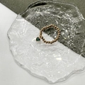 Detail of beaded gold ring featuring a heart-shaped green emerald pendant on glass - Gold-Emerald Green Zircon