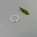 Macro-opname van handgemaakte kralenring met crèmekleurige kralen en een gouden accent - Stijl D Ronde Schelp (DR006-bai-D)