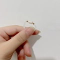 Detail van kralenring met witte matte kralen, barokparel en gouden accenten op de hand - Stijl C Parel (DR006-bai-C)