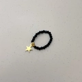Detalle de anillo de cuentas con piedras talladas negras y colgante de estrella dorada - Colgante de Estrella / Cuenta Negra