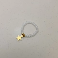 Primer plano de anillo elástico con cuentas de cristal y colgante estrella dorada - Colgante de Estrella / Cuentas Transparentes