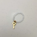 Detail van elastische kralenring met gouden hartvormige sleutelhanger voor vrouwen - Sleutelhanger / Transparante Kralen