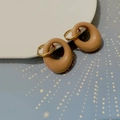 Dettaglio di orecchini in oro 18K con ciondoli in resina beige su porcellana bianca - Color Tè al Latte