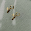 Détail de boucles d'oreilles étoiles dorées avec pierres naturelles œil de tigre - Style Étoile à Huit Branches