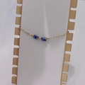 Detail of gold chain bracelet with square blue natural stones on a white display stand - Gold-Blue Spot