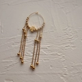 Vue rapprochée de la boucle d'oreille trèfle dorée avec chaînes à pompons perlées élégantes - Trèfle à quatre feuilles