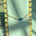 Close-up of double-layer gold titanium chain with oval blue stone and lobster clasp - White Blue Spotted Oval Gold