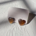 Macro-opname van amberkleurige hartvormige hars oorbellen met goudvlokken op kaart - Hart