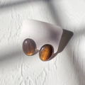 Detailopname van vintage ovale amberen oorbellen met gouden glitters op een kaart - Ovaal