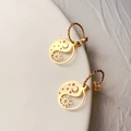 Gros plan détaillé des boucles d'oreilles soleil et lune en or 18 carats sur céramique - Style Creux Soleil Lune Yin Yang (麻花122)