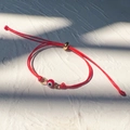 Primo piano del bracciale rosso con malocchio e chiusura a scorrimento dorata regolabile - Oro-Corda Rossa