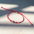 Dettaglio del bracciale rosso intrecciato con perla malocchio e chiusura a scorrimento - Argento-Corda Rossa