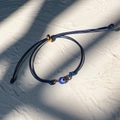 Detailed view of dark blue braided evil eye bracelet with adjustable golden slider bead - Gold-Dark Blue Rope