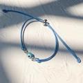 Detail of blue braided evil eye bracelet with adjustable silver sliding closure on stone - Silver-Sky Blue Rope