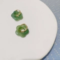 Boucles d'oreilles fleur évidée en résine verte avec anneau doré sur plateau blanc - Vert