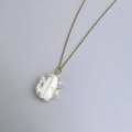 Macro shot of gold chain with irregular glass pendant and white textured interior detail - Gold-White