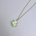 Detailed macro of a green wavy resin pendant necklace with gold leaf foil on gold chain - Gold-Green
