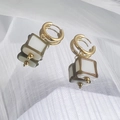 Détail de créoles dorées 18K avec pendentifs carrés en émail blanc sur tissu plissé - Blanc