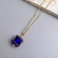 Detail of square blue glass pendant with gold textured frame and oval link chain - Gold-Blue