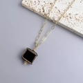 Detailed view of square black pendant with golden textured edges on gold link chain - Gold-Black