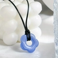 Dettaglio del ciondolo a fiore in resina blu su cordino nero con sfondo artistico chiaro - Blu