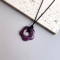 Macro shot of purple marble textured resin flower pendant necklace with black cord - Purple