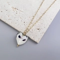 Dettaglio del ciondolo a cuore in vetro bianco con motivi neri su catena a graffetta d'oro - Oro - Texture Marmo Bianco