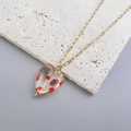 Macro view of a 3D heart-shaped glass pendant with red polka dots on a gold chain - Steel Transparent Red Dot