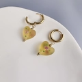 Detail von herzförmigen Glasohrringen mit mattem Rosenmuster an goldenen Reifen - Gelbes Herz-Gold