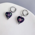 Close-up of heart-shaped purple glass earrings with pink rose detail on a white ceramic plate - Black Heart-Steel