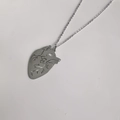 Gros plan du pendentif cœur anatomique argenté avec détails de texture évidés - Grand / Acier