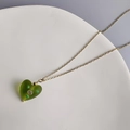 Gros plan d'un pendentif cœur en verre vert avec spirale artistique et chaîne dorée - Or-Vert