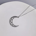Dettaglio del pendente a mezzaluna traforato su una catena in acciaio inossidabile argento - Verticale / Color Acciaio