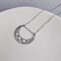 Dettaglio del ciondolo a mezzaluna d'argento con intricati motivi traforati sul supporto - Orizzontale / Color Acciaio